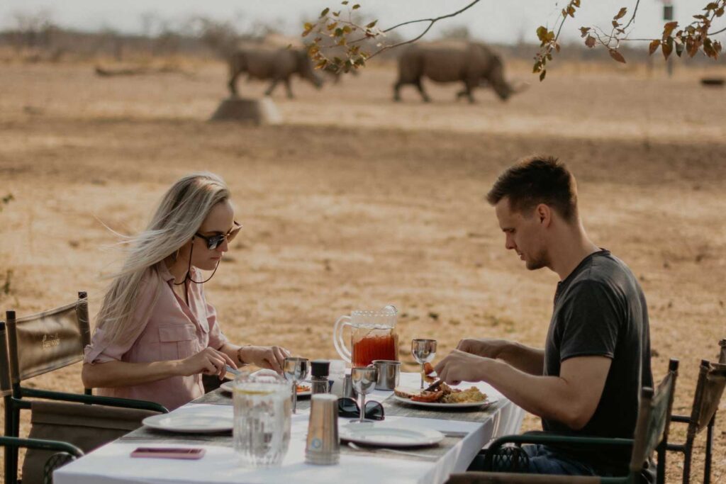 guests having brunch with rhinos in background